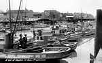 A postcard of Fishermans's Wharf, circa 1930, looking westward from the Taylor Street pier. Note the many masts folded down on top of the Monterey cabins to allow for passage under the arching pier. The row of boat and machine shops at the head of the skidways can be seen in the upper left. P86-029-01..
