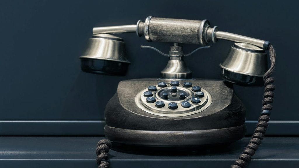 black and brown rotary phone near gray wall